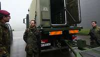 Alles klappt reibungslos Zwei Soldaten stehen vor einem Transportfahrzeug und beantworten die Fragen des Kommandeurs.