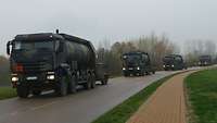 Vier Tankfahrzeuge mit Anhängern fahren um eine Kurve des Flugplatzes.