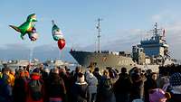 Mehrere Menschen in ziviler Kleidung stehen vor einem Boot der Deutschen Marine.