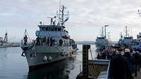 Zahlreiche Menschen stehen an der Pier und blicken auf ein Boot.