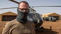 Ein Soldat steht vor einem Hubschrauber
