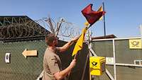Ein Soldat tauscht am Zaun der Feldpost eine rote gegen eine gelbe Flagge