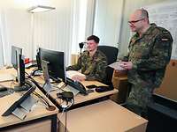 Abteilung Bürgerdialog Ein Soldat sitzt an einem Schreibtisch vor einem Computer, neben ihm steht ein anderer Soldat