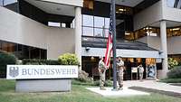 Service members hoist the American flag in front of the building of the Office of Defense Administration, U.S.A. and Canada