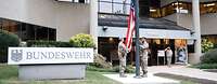 Service members hoist the American flag in front of the building of the Office of Defense Administration, U.S.A. and Canada