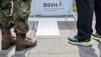 Blinden- und Sehbehindertenverein Hamburg Ein Soldat und ein ziviler Mitarbeiter haben einen Blindenstock in der Hand und probieren den Parcours aus