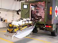 Der Tragentisch Ein militärisches Sanitätsfahrzeug in einer Halle. Der Tragentisch ist ausgefahren