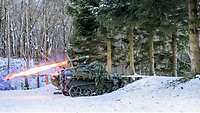 Ein Kettenfahrzeug steht im verschneiten Wald und schießt eine Panzerabwehrrakete ab.