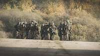 Eine Gruppe Soldaten läuft mit schwerem Gepäck eine ansteigende Straße hinauf. 