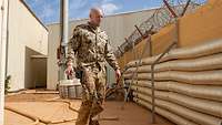 Ein Soldat im Feldanzug trägt Abwasserproben durch ein Lager