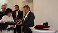 Ein Mann übergibt einer Frau eine Medaille