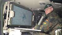 Der General sitzt in einem Gefechtsfahrzeug und schaut auf einen Bildschirm.