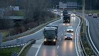 Bundeswehr-Fahrzeuge fahren in gleichmäßigen Abständen hintereinander auf einer Autobahn