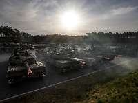 Fahrzeuge bei der VJTF-Übung Wettiner Schwert Mehrere Fahrzeuge stehen auf einem großen Platz bei tiefstehender Sonne. Dunst liegt in der Luft.