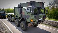 Ein Militär-LKW fährt auf einer asphaltierten Straße.