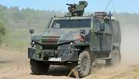 Ein gepanzertes Militärfahrzeug vom Typ Eagle V mit Maschinengewehr auf dem Dach fährt auf einem Sandweg