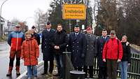 Soldaten, Fraktionsvorsitzende und der Bürgermeister stehen vor der Ortstafel.
