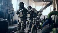 Mehrere Soldaten gehen mit der Waffe im Anschlag durch eine Fabrik.