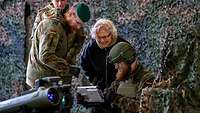 Ministerin Lambrecht besucht die Truppe Eine Zivilistin steht zwischen drei Soldaten vor einem Tarnnetz. Die Soldaten zeigen Waffentechnik.