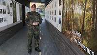 Ein Soldat im Feldanzug steht in einem langgestreckten Gebäude. An den Wänden sind großformatige Informations- und Bildtafeln.