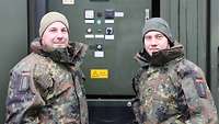 Zwei Soldaten stehen vor einem Stromerzeugungsaggregat