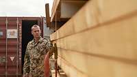 Ein Soldat steht neben einem Stapel Holzlatten