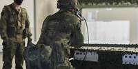 Ein Soldat schießt in Richtung einer Leinwand. Ein zweiter Soldat steht links daneben.
