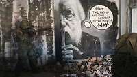Ein Soldat sichert den Zugang zum nächsten Raum ab, dabei steht er an einer Wand. An der Wand ist ein Street Art Gemälde.