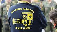 Ein Mann von hinten mit einem Logo vom Marinechor.