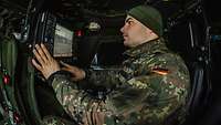 Waffenbediener Ein Soldat sitzt in einem Militärfahrzeug und bedient ein Gerät.