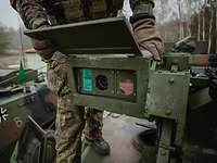 Optikmodul Ein Soldat steht auf einem Militärfahrzeug und öffnet einen Kasten mit Kamera, Wärmebildkamera und Laser