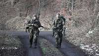Zwei Soldaten gehen auf einem Waldweg