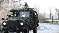 Ein getarnter Geländewagen mit Soldaten.