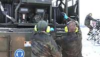 Zwei Soldaten bereiten den Tankschlauch und die Tankanlage am Tankwagen vor