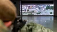 Schießübung an Zieldarstellungsanlage Soldat mit Waffe im Anschlag zielt auf interaktive Leinwand