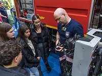 Jugendliche am Messestand Vier Jugendliche schauen einem Feuerwehrmann zu, der vor einem Feuerwehr-Kraftfahrzeug etwas erklärt.