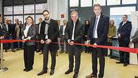 Four people cutting a red ribbon.