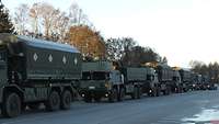 Mehrere Militärfahrzeuge stehen in einer Reihe auf einer Straße.