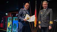 Ein Soldat übergibt einem Soldaten eine Urkunde und einen Preis.