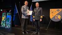 Ein Soldat übergibt einem Soldaten eine Urkunde und einen Preis.