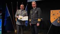 Ein Soldat übergibt einem Soldaten eine Urkunde und einen Preis.