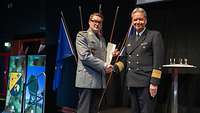 Ein Soldat übergibt einem Soldaten eine Urkunde und einen Preis.