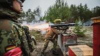 Ein Soldat schießt mit der Panzerfaust. Ein Feuerstrahl tritt hinten aus dem Rohr aus.