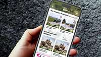 Eine Hand hält ein Handy mit der Radio Andernach App drauf.