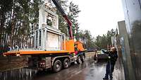 Ein Lastwagen mit Kran, auf diesen werden Betonelemente verladen.