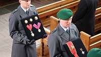 Soldaten vom Wachbataillon laufen durch eine Kirche und tragen Orden auf einem Kissen.