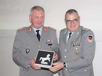 Zwei Soldaten reichen sich die Hände. Einer übergibt dem anderen ein Geschenk.