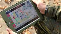 Ein Mensch in Uniform hält ein Tablet in Händen, worauf zu sehen ist, wie die Wasseraufbereitung in Echtzeit läuft