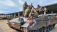 Wartung und Instandhaltung des Schützenpanzer Marders Zwei deutsche Soldaten steht mit griechischen Soldaten auf einem Schützenpanzer Marder und erklären etwas.