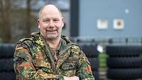 Ein Soldat steht mit verschränkten Armen vor einigen Reifen